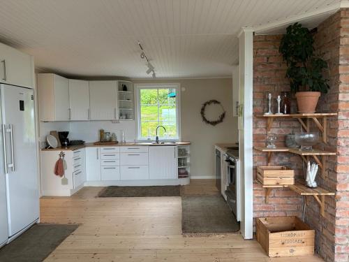 a kitchen with white cabinets and a brick wall at house with a view in Huskvarna