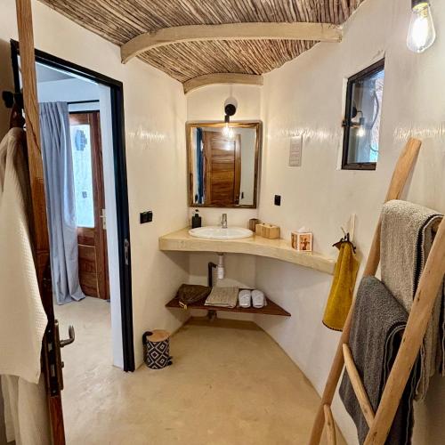 une salle de bain avec un lavabo et un miroir dans l'établissement Maison Fimela, à Fimela