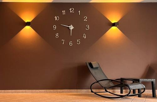 a clock on a wall with a chair and lights at Hotel Rio Bianco in Panchia