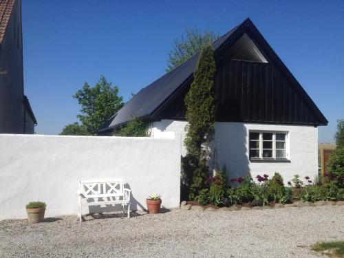 a white house with a black roof and a white bench at Arnhög Farm in Borrby