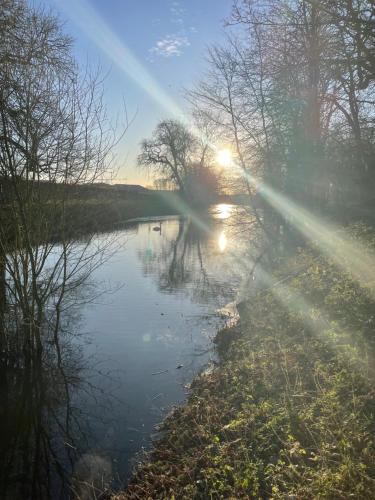 a river with the sun reflecting in the water at Wimbish Hall Cabins in Wimbish
