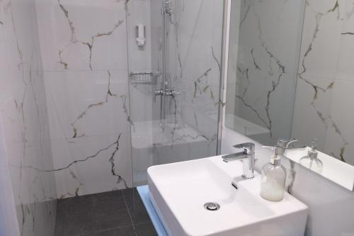 a white bathroom with a sink and a shower at City Center Studios by Cretan Houses in Heraklio