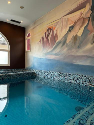 a swimming pool with a mountain mural on the wall at Hotel Rio Bianco in Panchia