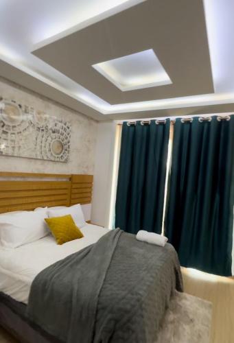 ルサカにあるCactus Apartmentsのベッドルーム1室(青いカーテン付きの大型ベッド1台付)