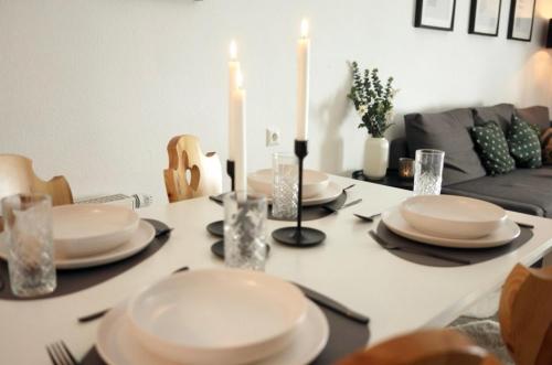 a dining room table with white plates and candles at Ferienhaus Nr 47, Kategorie Premium, Feriendorf Hochbergle, Allgäu in Lechbruck