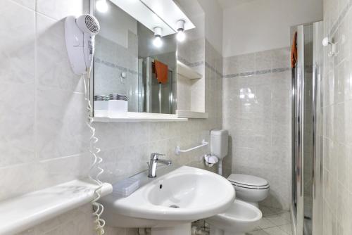 a white bathroom with a sink and a toilet at Residence Le Mimose in Procchio