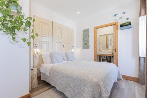 a white bedroom with a bed with blue pillows at NINHO SALOIO in Venda do Pinheiro