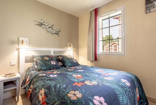 une chambre avec un lit avec une couette bleue et une fenêtre dans l'établissement L'esquiròu, proche du lac, résidence avec piscine, à Biscarrosse