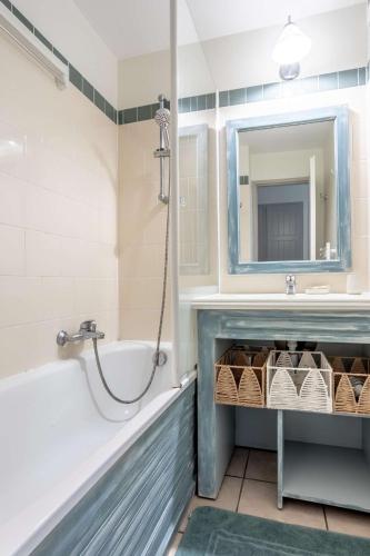 une salle de bain avec une baignoire, un lavabo et un miroir dans l'établissement L'esquiròu, proche du lac, résidence avec piscine, à Biscarrosse