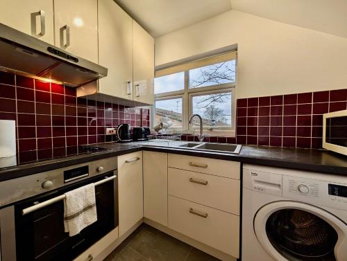 a kitchen with a sink and a washing machine at Stunning Property with Garden and Parking in Finchley