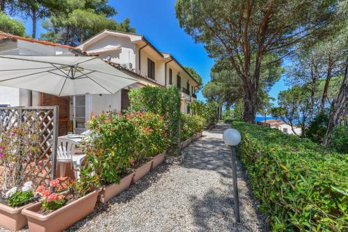 a house with an umbrella and some plants at Residence Le Mimose in Procchio