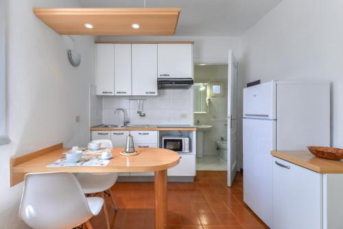 a kitchen with a wooden table and a white refrigerator at Residence Le Mimose in Procchio