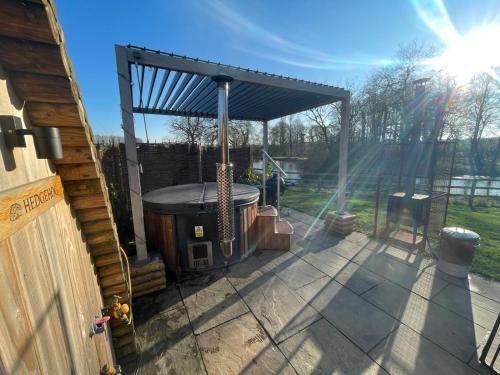 a gazebo with a hot tub on a patio at Wimbish Hall Cabins in Wimbish