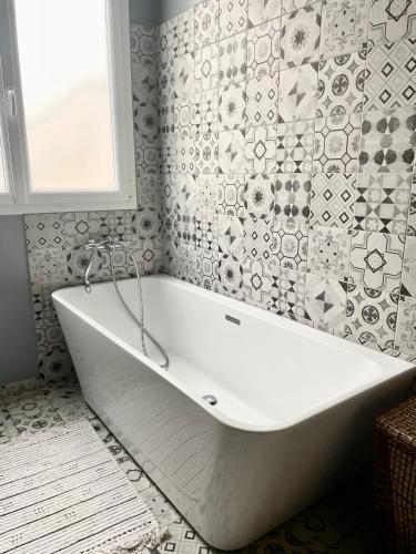 a white bath tub in a bathroom with a window at Le Lodge Champenois in Épernay