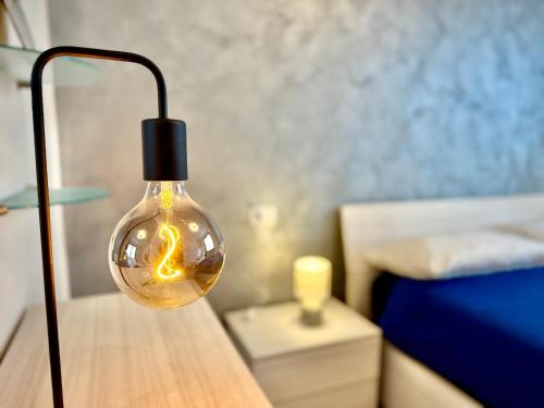 a light bulb on a table next to a bed at Airport House 2' from MXP, 15' public shuttle free in Case Nuove