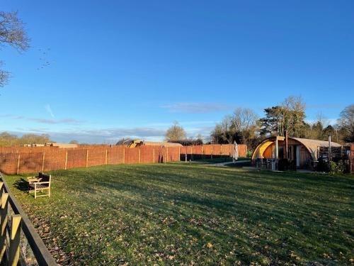a grassy field with a fence in the background at Wimbish Hall Cabins in Wimbish