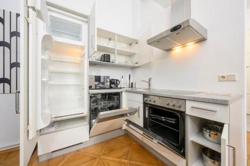 a kitchen with white cabinets and an open refrigerator at Spacious apartment in Graz for 6 people in Graz