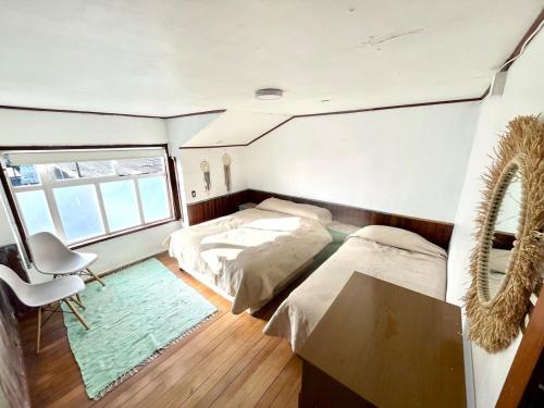 une chambre avec deux lits et un bureau et une fenêtre dans l'établissement Casa Vintage Puerto Varas, à Puerto Varas