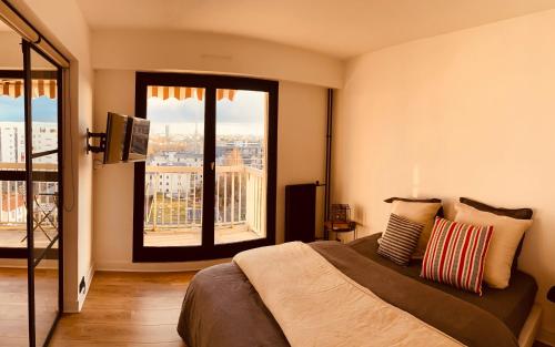 une chambre avec un lit et une grande fenêtre dans l'établissement Appartement vue Paris, à Courbevoie