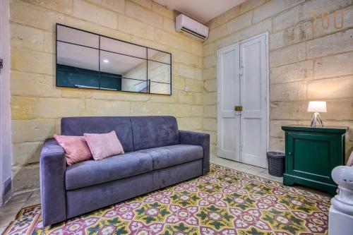 a living room with a blue couch and a window at Authentic studio with Maltese Balcony in Bormla by 360 Estates in Taʼ Penza