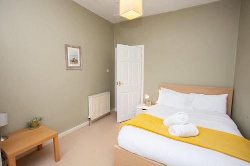 a bedroom with a bed with two towels on it at 3 Bed Cottage Flat with Parking in Glasgow