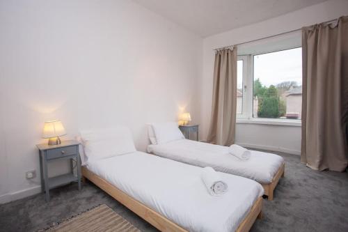 two beds in a room with a window at 3 Bed Cottage Flat with Parking in Glasgow