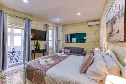 a bedroom with a large bed and a living room at Authentic studio with Maltese Balcony in Bormla by 360 Estates in Taʼ Penza