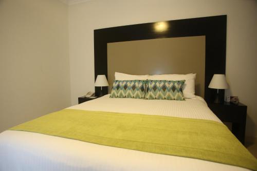 a bedroom with a large bed with a black headboard at Aranjuez Hotel & Suites in David