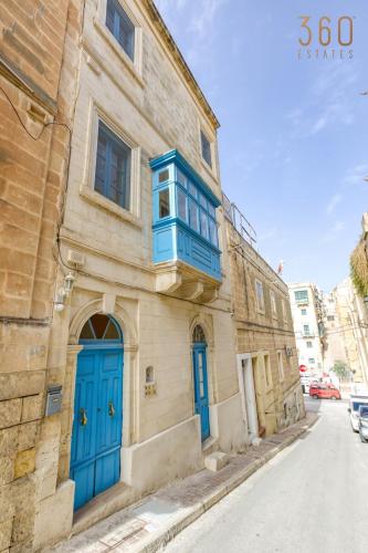 a building with blue doors and a balcony on a street at Authentic studio with Maltese Balcony in Bormla by 360 Estates in Taʼ Penza
