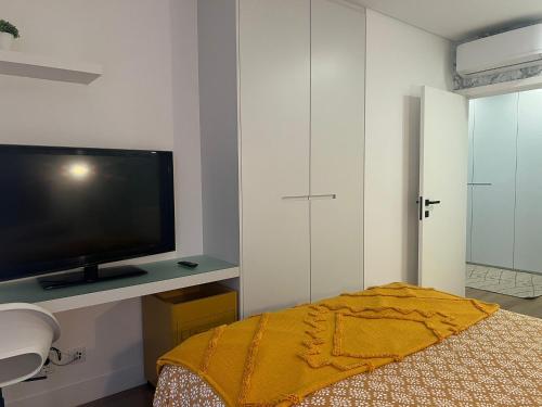a bedroom with a flat screen tv and a bed at Coração do Castelo AL in Castelo Branco