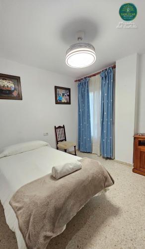 a bedroom with a large bed with blue curtains at Mirador del Castillo by Sanlúcar Housing in Sanlúcar de Barrameda