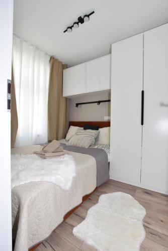 two beds in a bedroom with white cabinets at Apartamenty K netflix wi-fi gratis in Wałbrzych