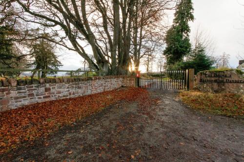 a stone fence with a gate in a yard at The Doune, Luxury Traditional Country House with hot tub in Inverness