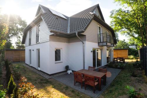 ein kleines weißes Haus mit einem Tisch und Stühlen in der Unterkunft Ferienwohnungen am Darßer Ort inkl Wäschepaket in Wieck