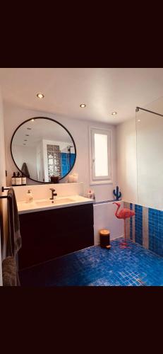 une salle de bain avec un lavabo et un miroir dans l'établissement Appartement vue Paris, à Courbevoie