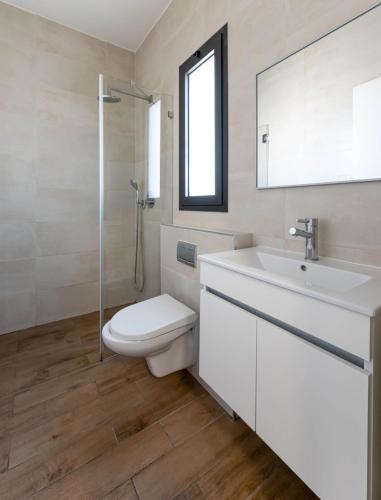 a white bathroom with a toilet and a sink at פנינת הקריות in Qiryat Ata