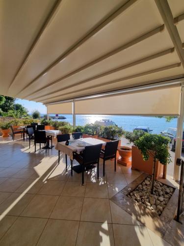 a patio with tables and chairs and a view of the ocean at Hotel Zlatna Vala in Umag