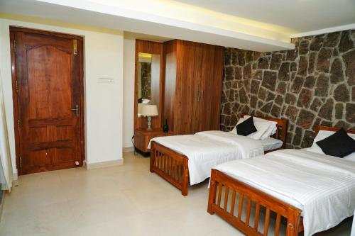a bedroom with two beds and a wooden door at Wanderville in Vagamon