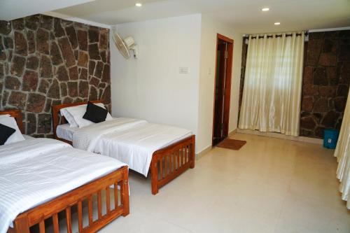 a bedroom with two beds and a stone wall at Wanderville in Vagamon