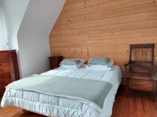 une chambre avec un lit et un mur en bois dans l'établissement Ty Marion, plage et commerces à pied, à Fouesnant