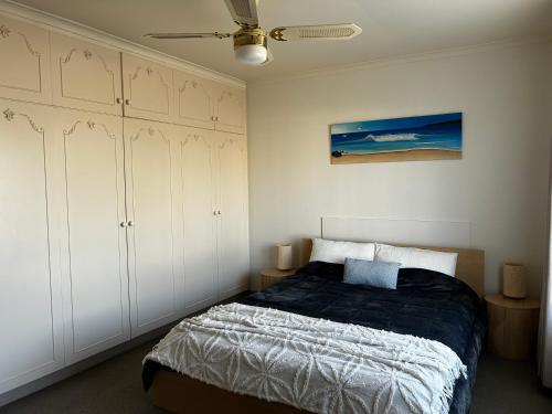 a bedroom with a bed and some white cabinets at Boho Beach Haven in Port Adelaide