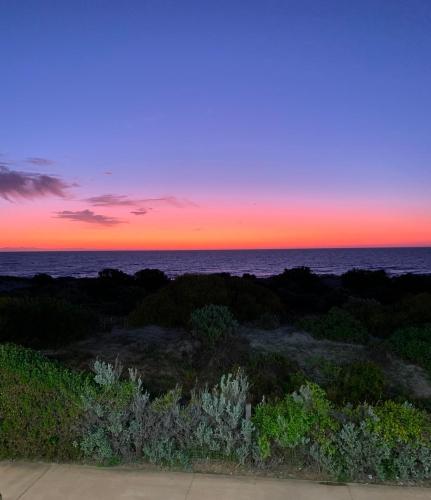 a sunset over the ocean from a balcony at Boho Beach Haven in Port Adelaide