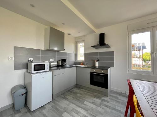 - une cuisine avec des appareils électroménagers blancs et une table dans l'établissement Bellavista #3 by Melrose, à Arromanches-les-Bains