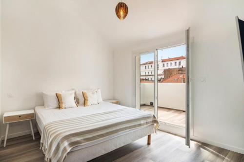 une chambre blanche avec un lit et une grande fenêtre dans l'établissement 3 bedrooms 2 terraces in Cannes, à Cannes