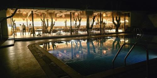 a swimming pool with tables and chairs in a building at Menaka inn in Dhārwād