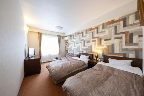 a hotel room with two beds and a large wall at tanoshic resort 西紀荘 in Ubara