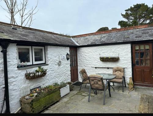 a table and chairs sitting outside of a white cottage at The Stable -Plymouth in Plymouth