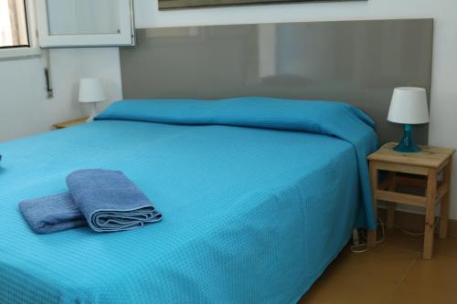 a bed with blue sheets and towels on it at Rocca dei tramonti in Punta Braccetto