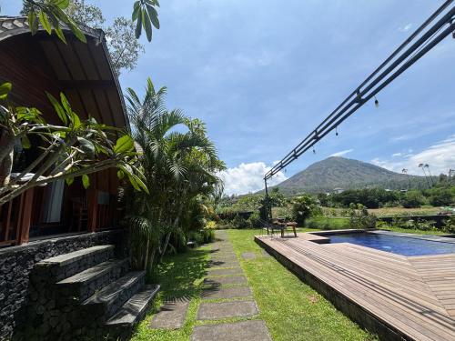 a house with a wooden deck and a swimming pool at Batur garden in Kubupenlokan