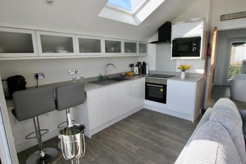 a kitchen with white cabinets and a sink at Kittiwake Retreat, a luxury escape by the sea! in Gorran Haven